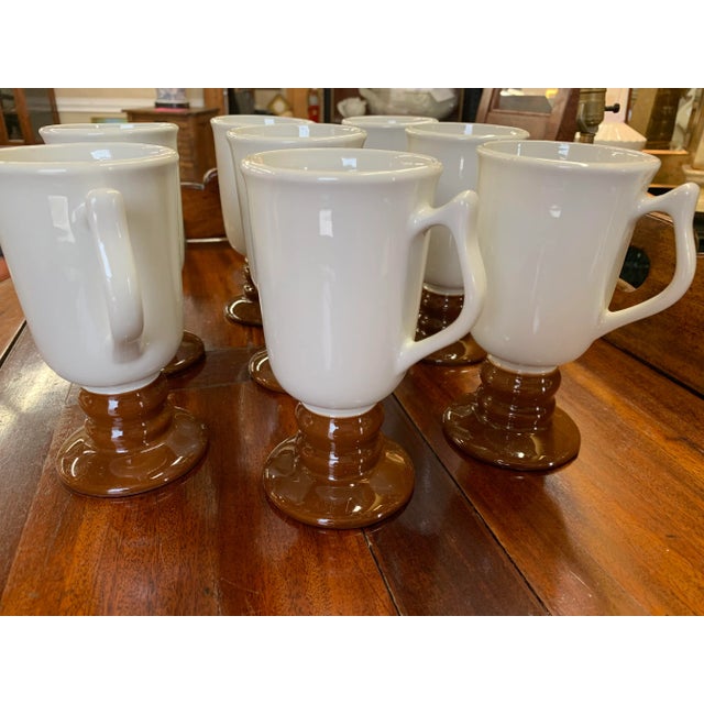 Set of 8 footed vintage ceramic mugs by Hall. Colored in a creamy white with a “milk chocolate” bottom. Marked 1273....