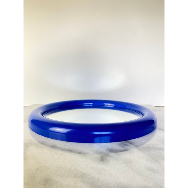Playful and sculptural vintage postmodern wall mirror featuring a bold primary blue molded frame and clean circular...