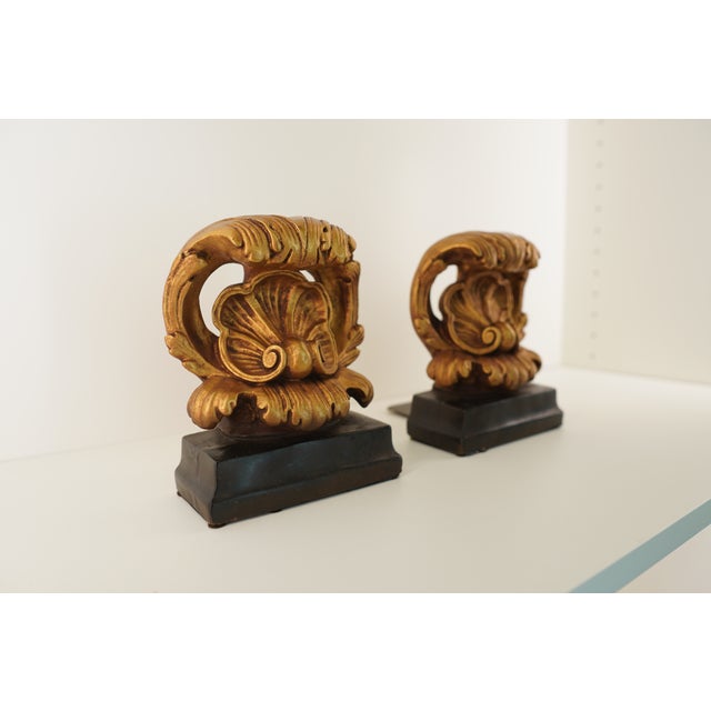 This decorative pair features two small metal sculptural forms mounted on black bases, designed as complementary accent...
