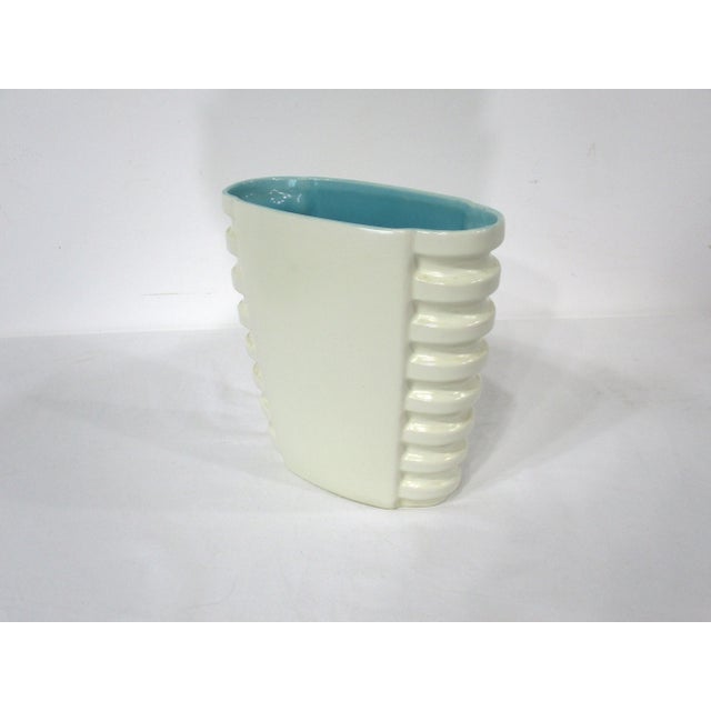 A very nicely designed smooth creamy white glaze with side ribbing to the form and a turquoise interior . The tapered vase...