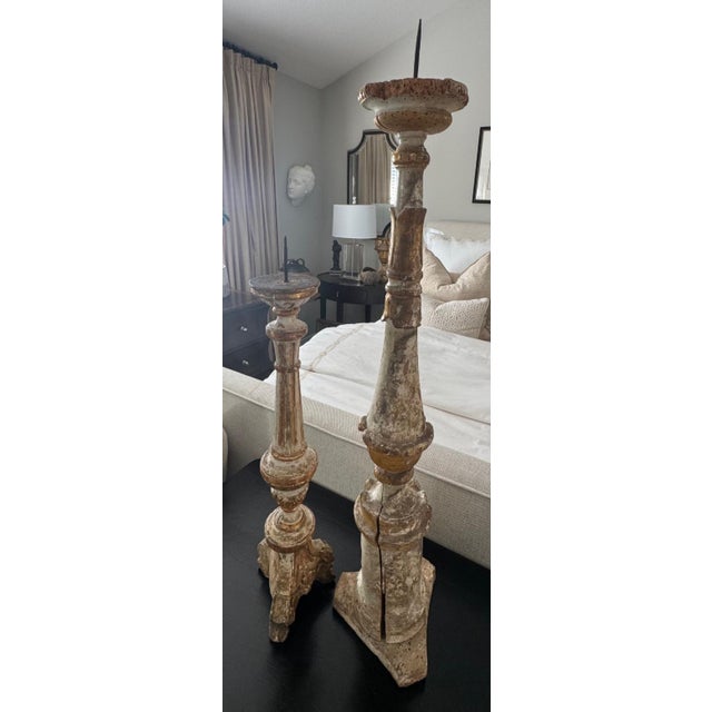 Architectural asymmetrical pair of antique Italian carved wood candlesticks featuring a heavily timeworn painted surface...