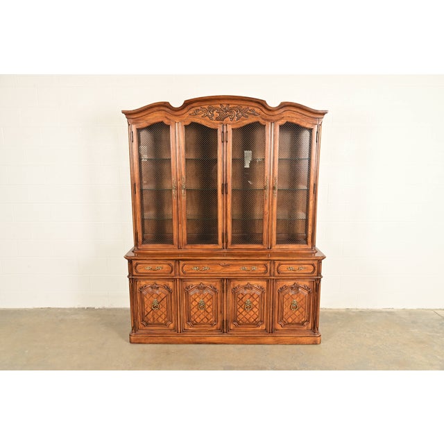 A beautiful French Regency Louis XVI style lighted breakfront bookcase or dining cabinet By Thomasville USA, 1980s Carved...