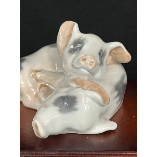 This charming Royal Copenhagen figurine captures a sweet moment between two resting pigs, sculpted with warmth and...