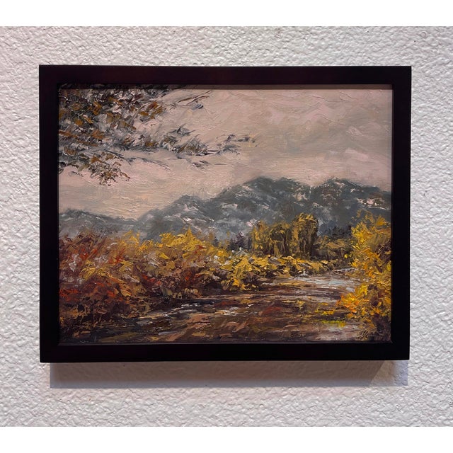 The painting depicts a serene landscape of Taos, showcasing a winding river surrounded by lush foliage and distant...