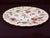 This distinctive porcelain plate has a colorful floral motif and features a scalloped and embossed rim with gold trim.