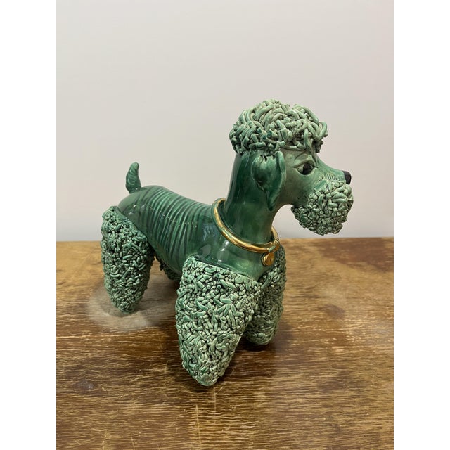 This large 25 cm poodle is finished in the iconic, deep-green lead glaze that made the ateliers of Vallauris famous. While...