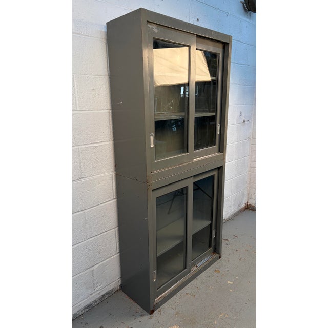 A striking industrial metal cabinet featuring a smooth sliding glass door and a clean, utilitarian silhouette. Combines...