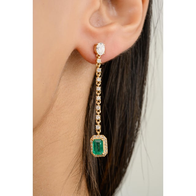Elevate your style with these modern allure emerald dangling earrings. Featuring radiant emeralds and brilliant diamonds,...