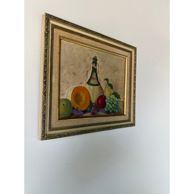 Charming 1970s still life oil painting titled “Fruit and Wine” by artist Frances Heller. Executed on canvas board, the...