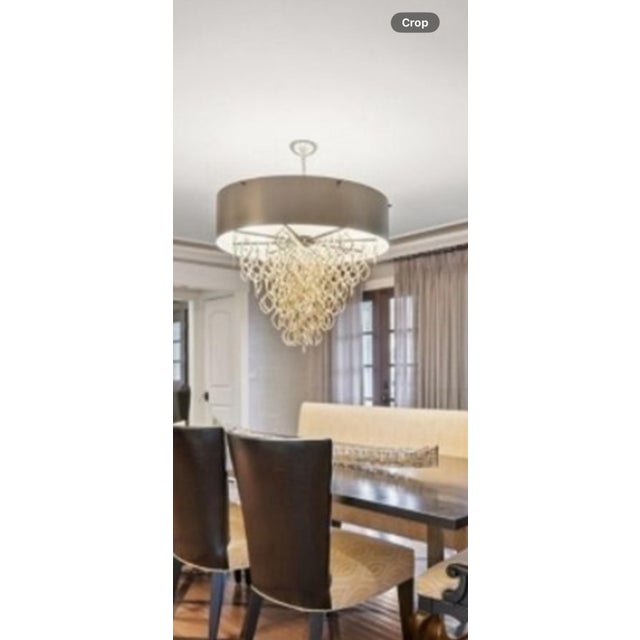 Rows of brass chain contrastingly cascade from the bronze metal shade. Light is diffused through frosted glass. It’s a...