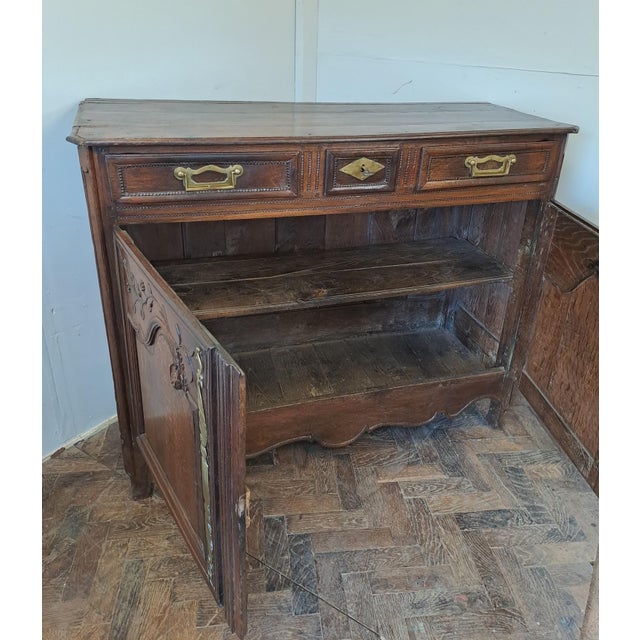 This elegant French carved oak buffet is a charming example of provincial craftsmanship. It features a beautifully aged...