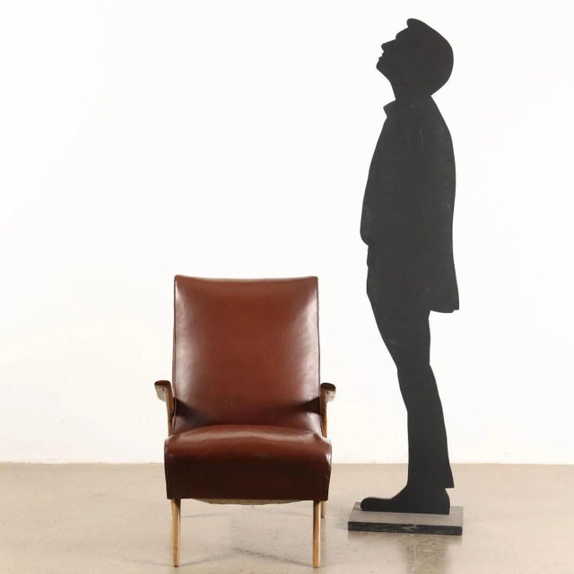 Spring-upholstered armchair, upholstered in leatherette with wooden legs and armrests. This piece is attributed to the...