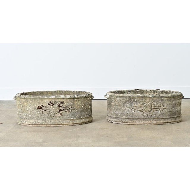 An inspirational pair of English cast stone planters from the 1920s decorated with Italianate “sun” motifs wrapping across...