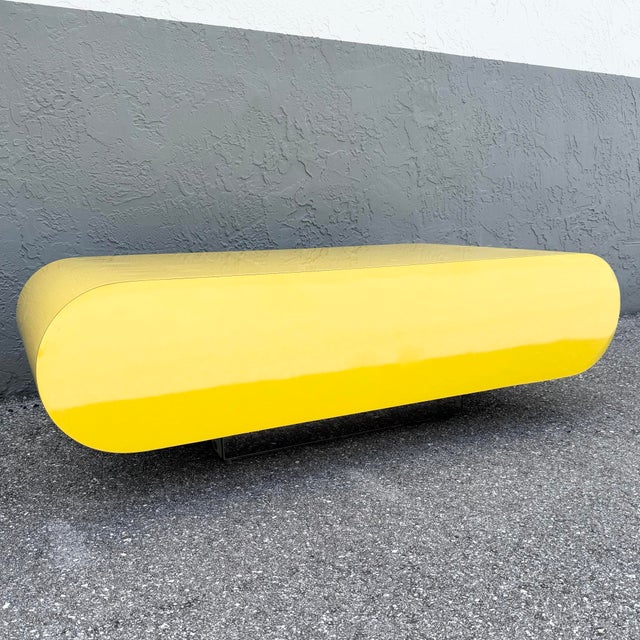 This striking Postmodern coffee table makes a bold sculptural statement with its sleek bullnose silhouette and vibrant...