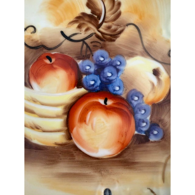 Vintage Japanese hand-painted porcelain fruit bowl featuring peaches, grapes, and bananas, accented with gilt scrollwork,...