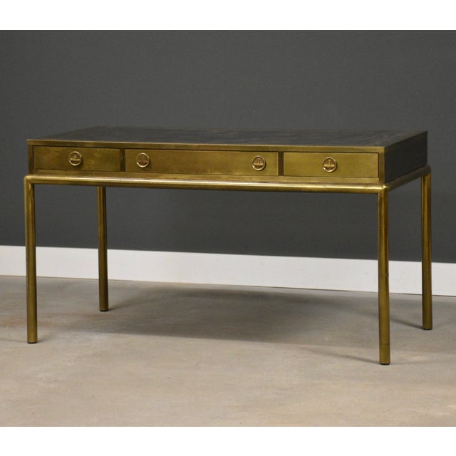 A Hollywood Regency style brass desk with a tooled leather top made by Mastercraft Furniture. 56” wide. 27.5” deep. 31” tall.