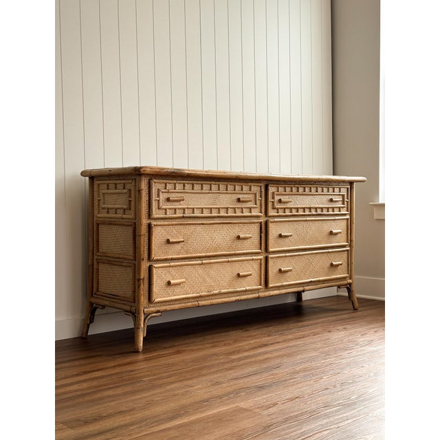 Vintage rattan and bamboo six-drawer dresser with geometric detailing, the woven surfaces creating a rich, textural...