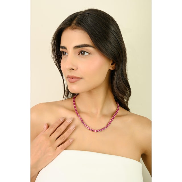 This vivid 14K yellow gold tennis necklace features a continuous line of 71 emerald-cut rubies totaling 50.19 carats, each...