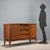 Vintage sideboard with drop-down doors and open central drawers. Teak and burl veneer. This piece is attributed to the...