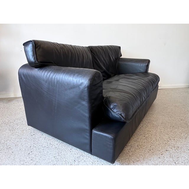 A sofa * a 2-seater sofa * made of black leather * by arcon italia * postmodern design from the 1980s * with geometrically...