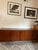 The item is a low wooden credenza featuring a rectangular top, four sliding cabinet doors with small hardware pulls, and a...