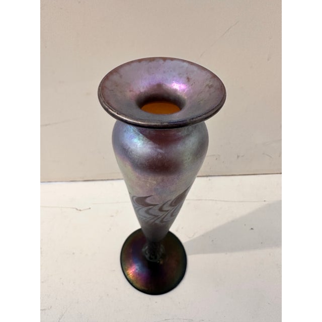 This signed hand‑blown art glass vessel features a tall, slender silhouette with a flared rim and wide base. The surface...