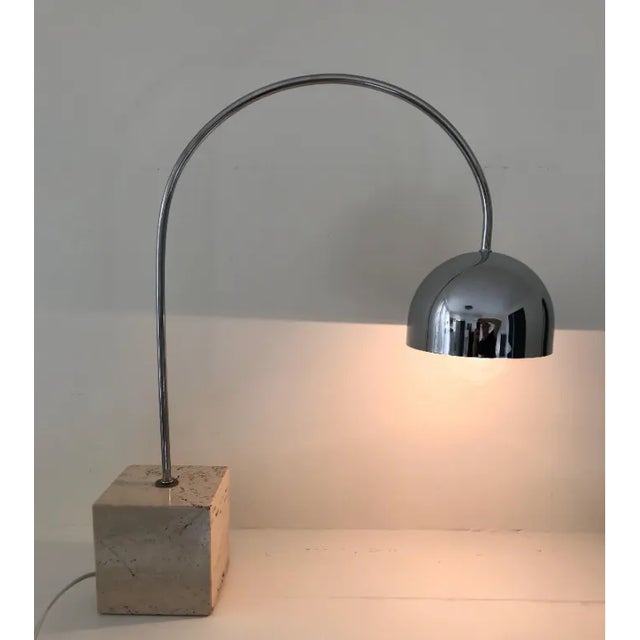 Very cool arc table or desk lamp in chrome, anchored with square travertine block base. Made in Italy by Harvey Guzzini....
