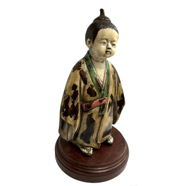 A vintage japanese lamp features a figural porcelain depicting a Geisha in multi colors, fitted atop a circular wooden...