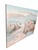A tranquil Southwestern landscape featuring adobe-style buildings nestled beneath a sweeping mountain range. Soft peach,...