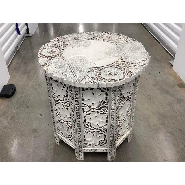 Charming Moroccan side table. Made of teak and painted white, this table features a well-carved leaf and vine pattern on...