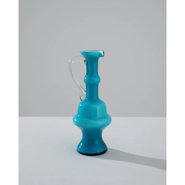 Behold a piece of Italian history with this stunning 1960s Italian Blue Glass Jug, an embodiment of form and function in...