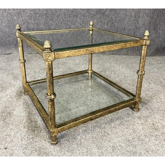 This petite metal and glass side table features a delicate, airy frame topped with a clear glass surface that keeps the...