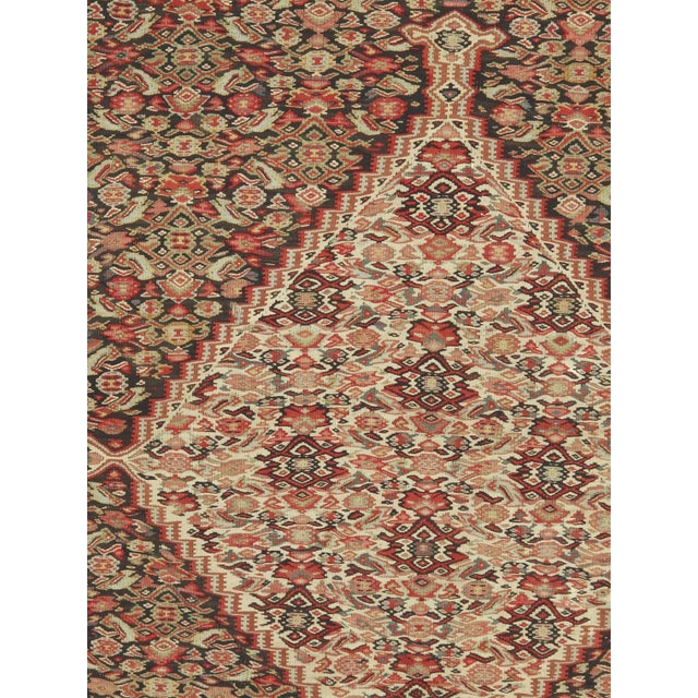 An antique Persian Senneh flatwoven rug from Kurdistan in western Iran, featuring a finely detailed Herati design across a...