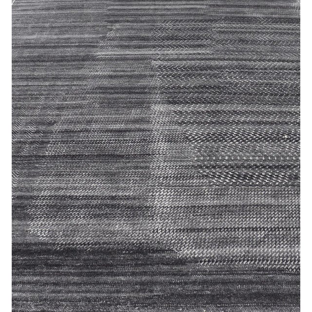 This modern abstract rug was hand-knotted with wool in India. The design features no definite pattern, but "scrapes" of...