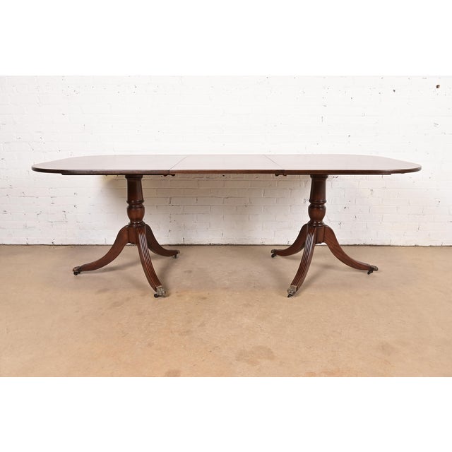 An exceptional Georgian or Regency style double pedestal extension dining table In the manner of Baker Furniture USA,...