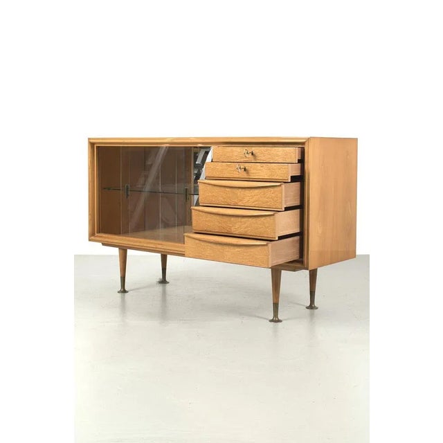Extraordinary, Typical 50s Style, Blond Veneer Sideboard with Display. This dresser has elegant wooden legs with brass...