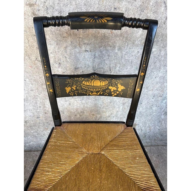 This product is a pair of antique Hitchcock stenciled rush seat side chairs, featuring a floral pattern on dark wood...