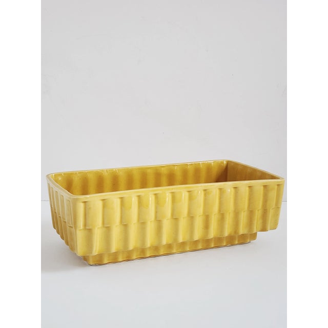 Offering a Mid Century Modern yellow ceramic cachepot or planter by Cookson Pottery, Roseville Ohio, USA. The rectangular...