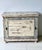 This charming rustic vintage cabinet features a heavily distressed white paint finish with subtle blue undertones,...