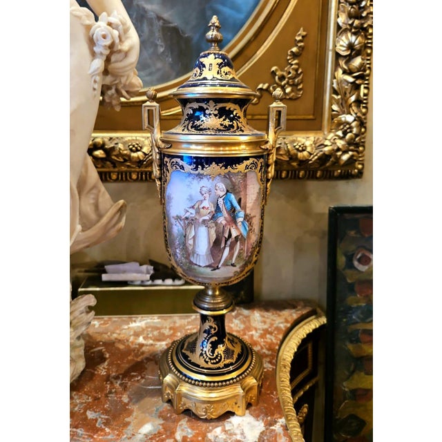 This exquisite French-style porcelain vase features a deep cobalt blue ground richly decorated with gilded motifs and an...