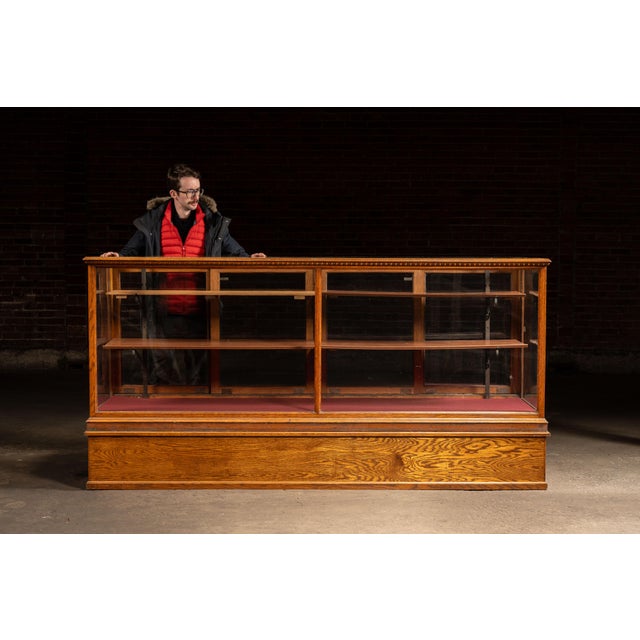 Large-format retail showcase constructed in quarter-sawn oak with expansive glass panels and a deep, paneled storage base....