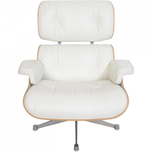 Vitra Charles Eames Lounge chair with ottoman upholstered in white leather and with a shell of light walnut. The chair is...