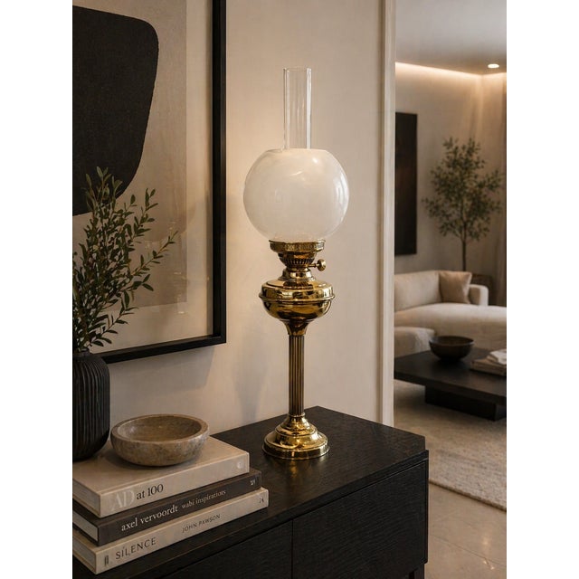 An antique Edwardian English brass oil lamp of elegant form featuring a fluted column, circular reservoir and a classic...