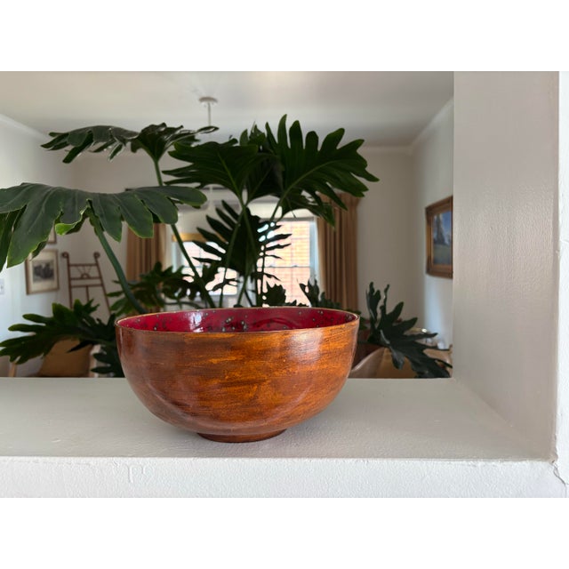 Stunning large glazed pottery bowl made in 1961 by Anne N. Interior red is brilliant against the outer brown wood look....