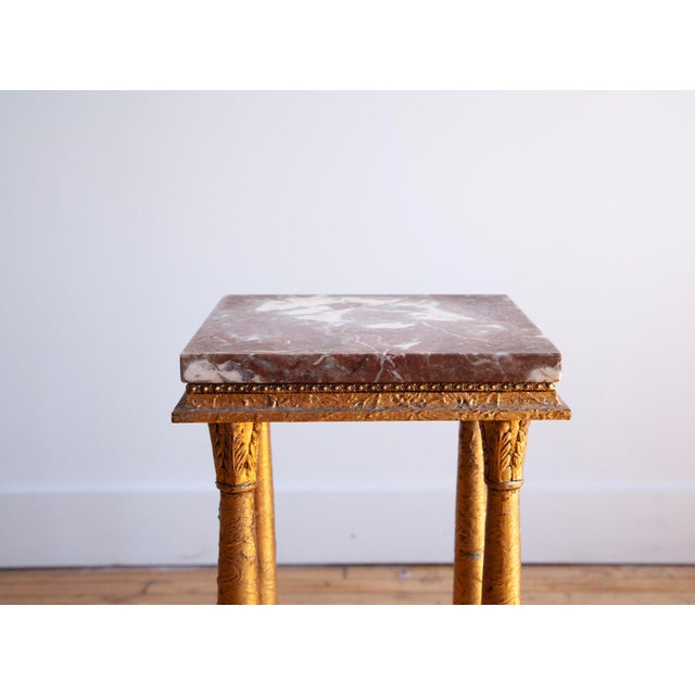 Empire style marble-top gilded plant stand or pedestal. Lovely piece with paw feet and carved details. Photos show...