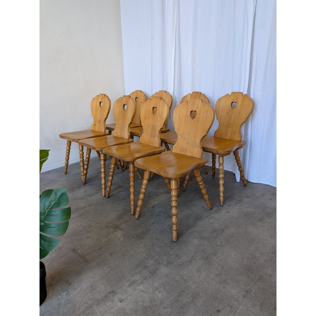 Set of 8 vintage wooden dining chairs in Tyrolean style. The chairs feature solid wooden construction with bobbin-turned...