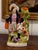 Figure in a plumed hat, purple jacket and striped kilt stands beside a green tree trunk spill with a dog alongside. Lively...