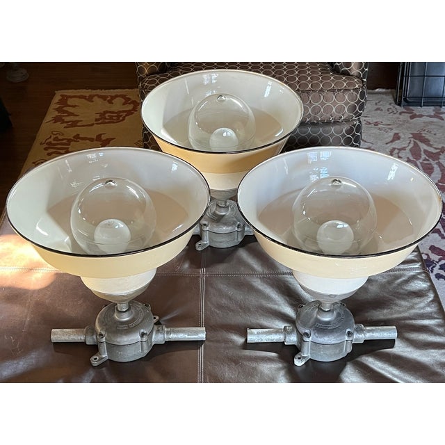 White enameled shades patined ivory are is complemented by black porcelain rims that marks the shades early 1940's...