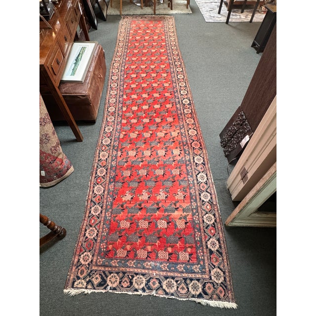 Design Plus Gallery presents a 3ft 8in × 16ft Hand-Knotted Persian Runner. The runner rug showcases a red field with...