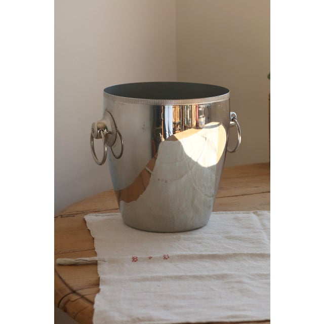 A silver-plated metal ice bucket by Rémy Letang, with a clean and elegant design, enhanced by two side ring handles for...